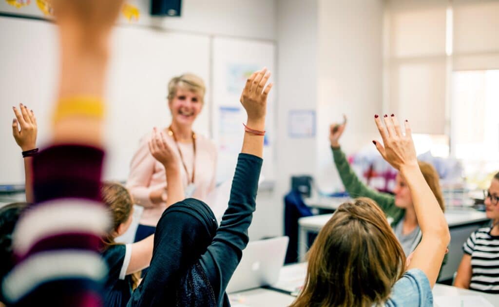 Students with their hands up responding to their teacher