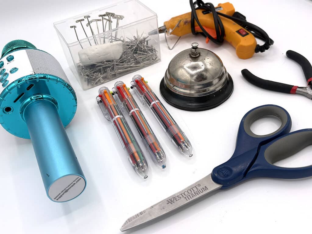 microphone, multicolor click pens, t-pins, hot glue gun, bell, scissors, pliers