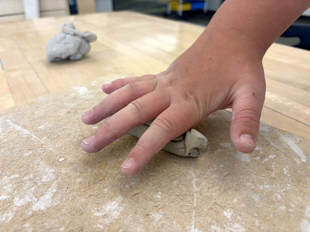 hand pushing clay