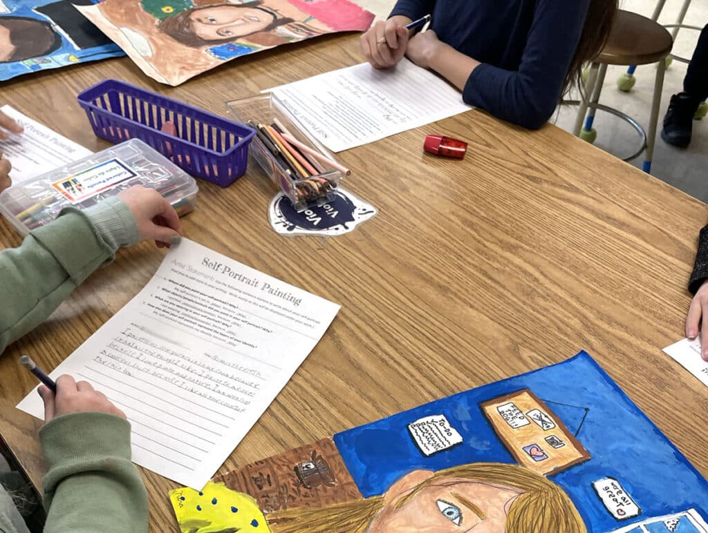 students writing artist statements with self-portraits