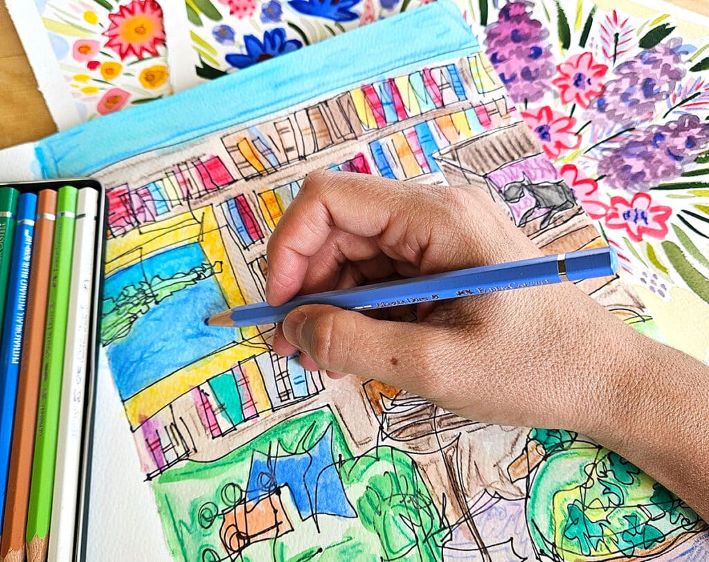 hand with colored pencil and pile of artwork