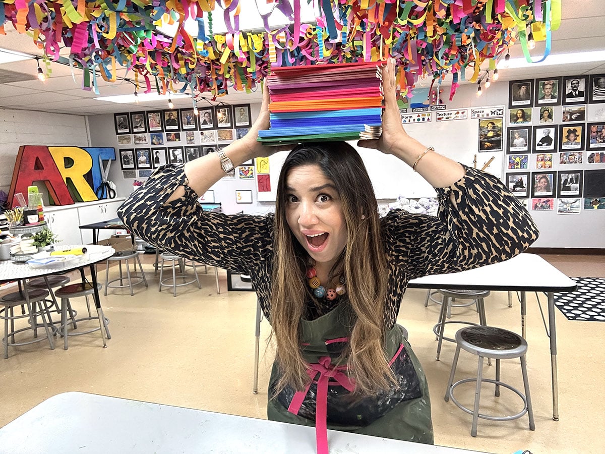 nylah khan with a pile of sketchbooks on her head