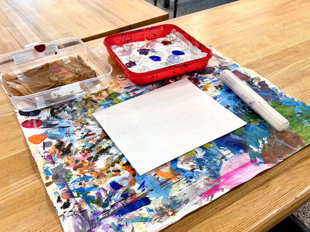 messy mat with paint and paper